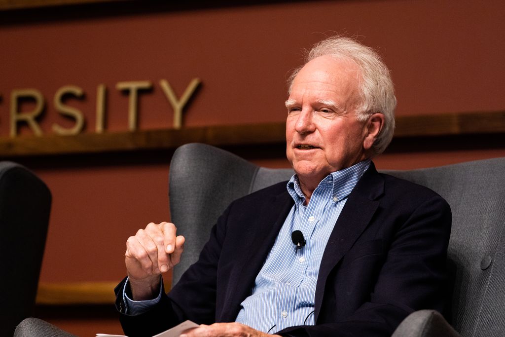 Robert Hall gestures while speaking in an armchair at a panel discussion.