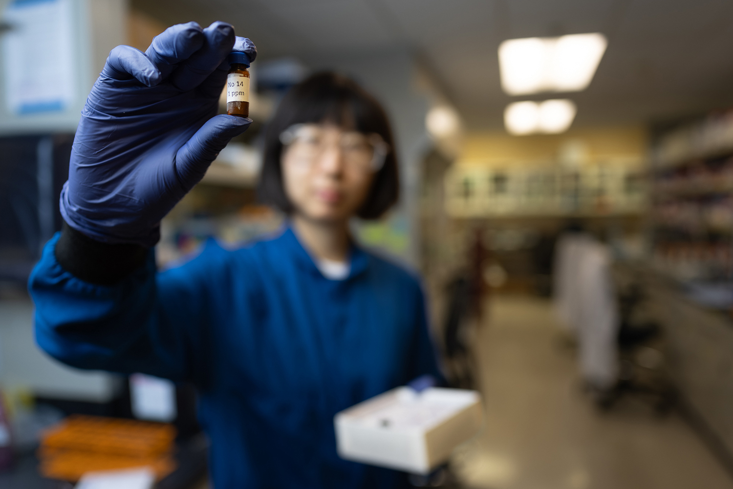 Nina Zhao holds up a small labeled sample vial