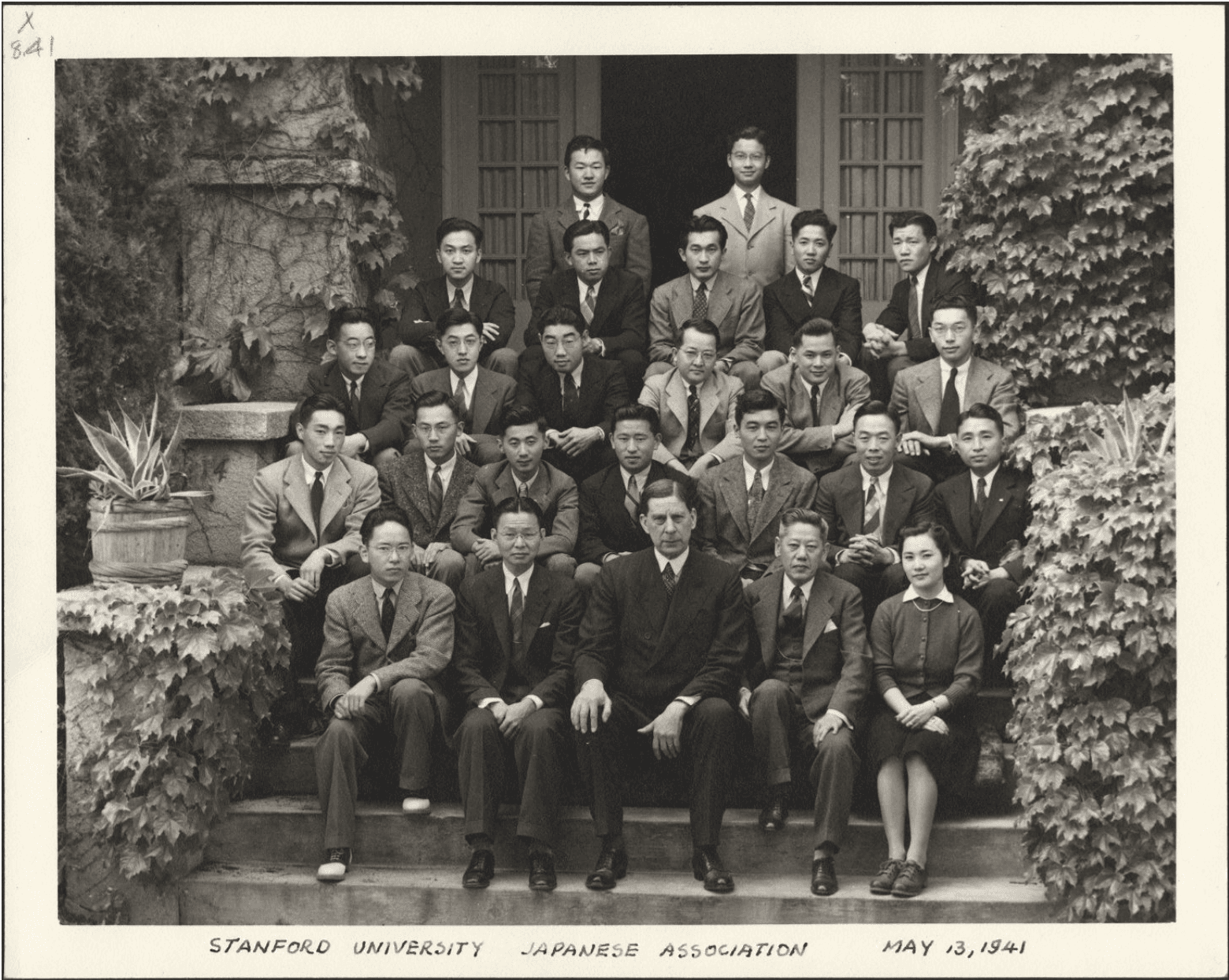 Group portrait of the Stanford University Japanese Association members seated on steps, surrounded by greenery, taken on May 13, 1941.