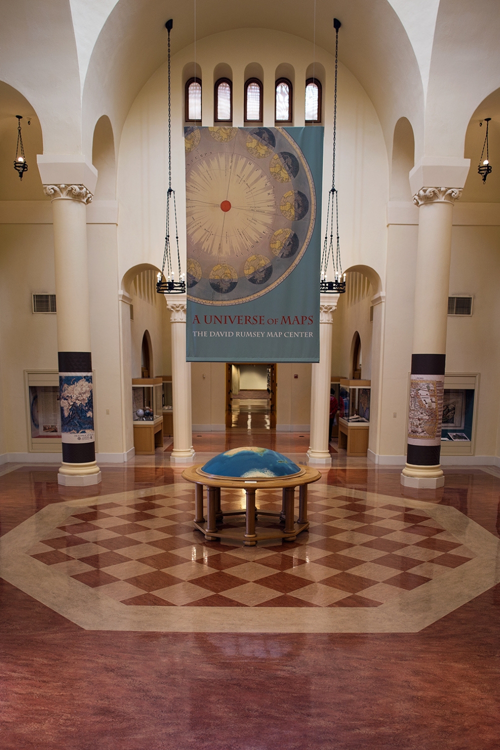 A spacious museum hall features a large globe table and a banner reading 