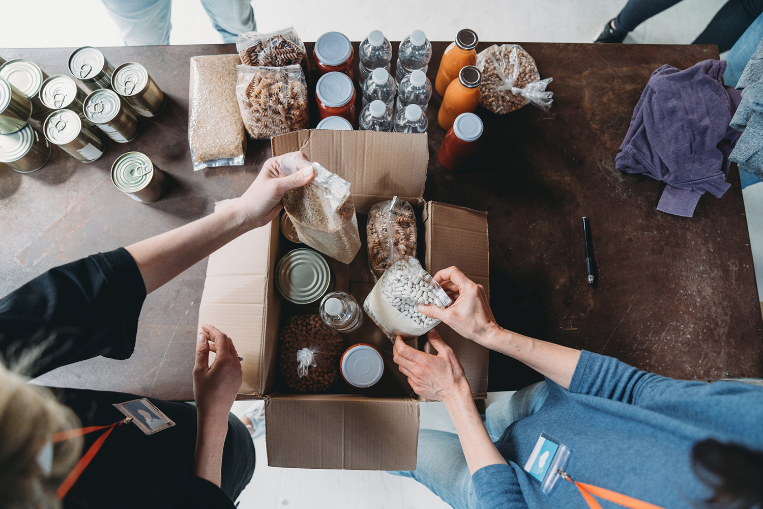High-angle view of volunteers preparing a box of food and drink at a food bank.