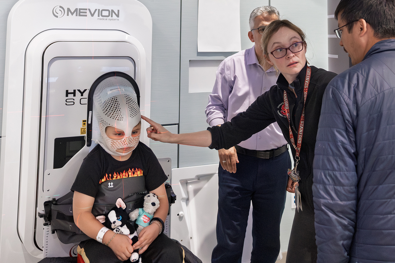 A child with toys sits in a medical chair while staff prepares them for treatment, focused on comfort and reassurance.