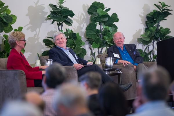 Three members of a panel in front of an audience.