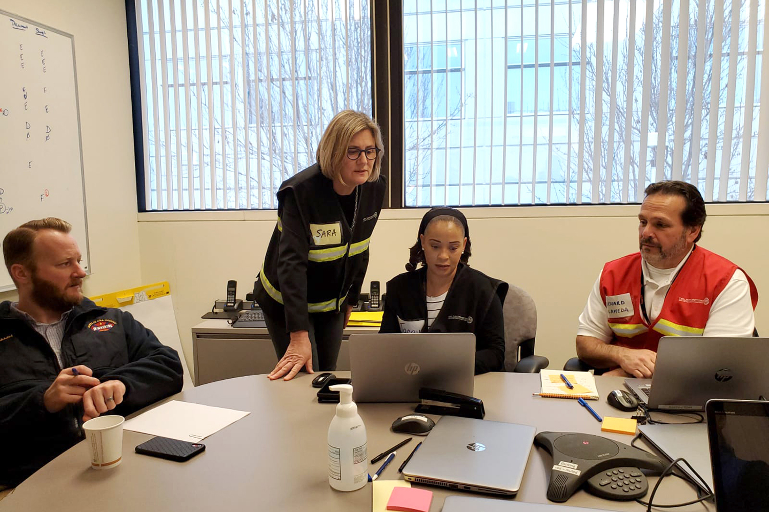 Dr. Sara Cody standing hunched over a table with other emergency coordinators.