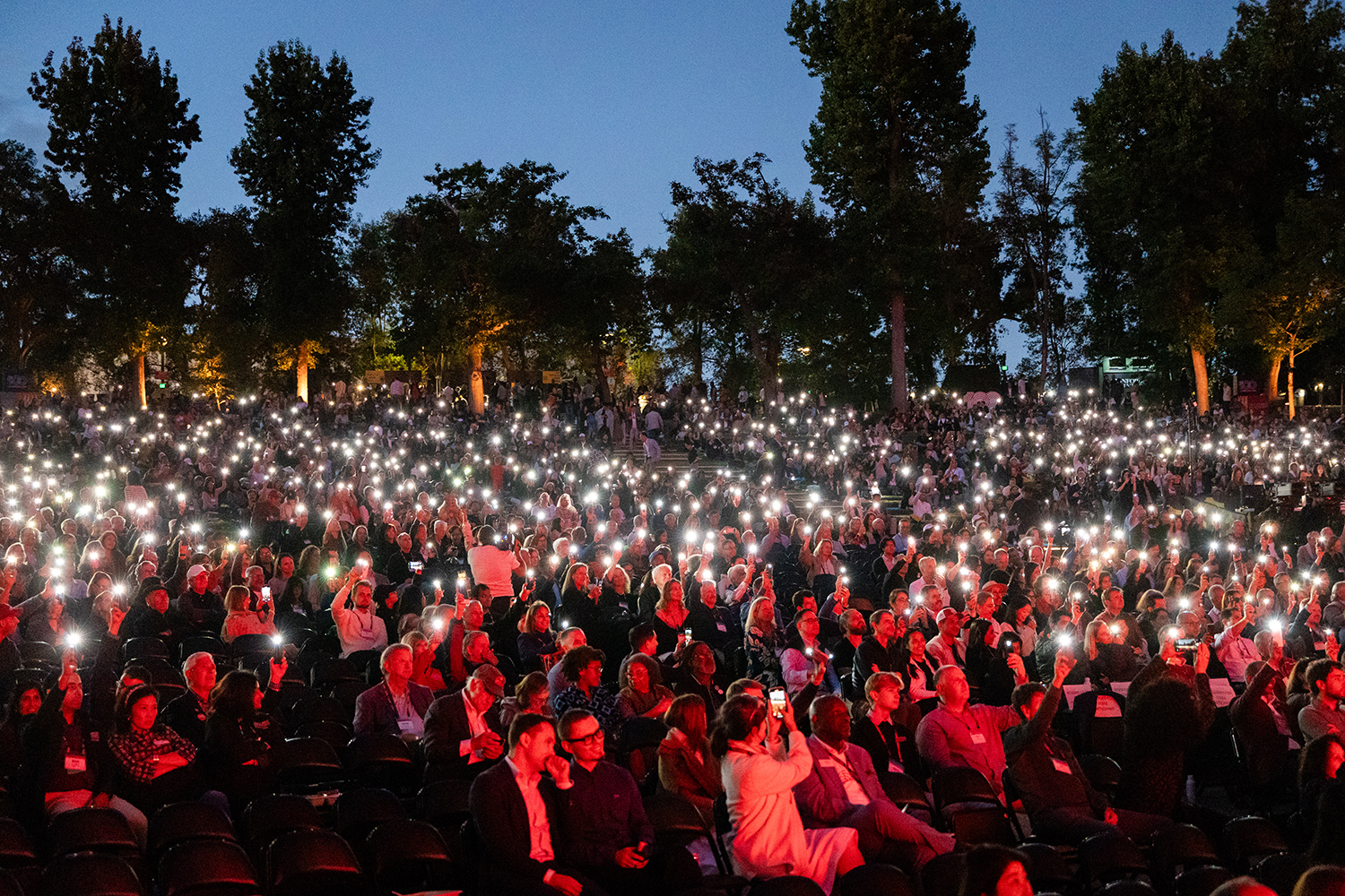 Audience members shine their cellphone flashlights.