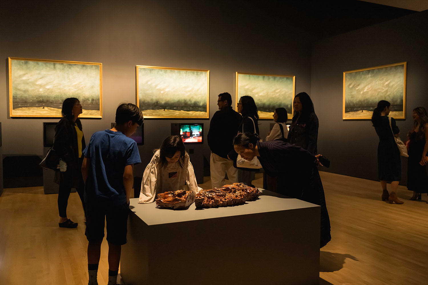 Visitors explore a gallery with landscape paintings and sculptures on display.