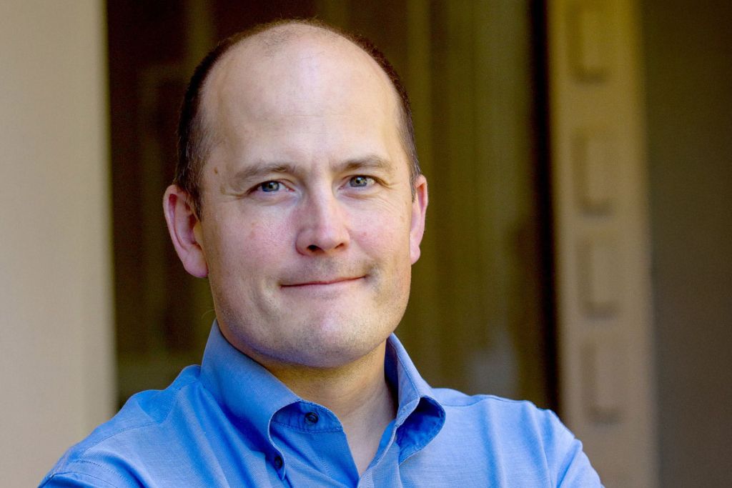 Paul Bollyky headshot in blue shirt in outdoor setting.