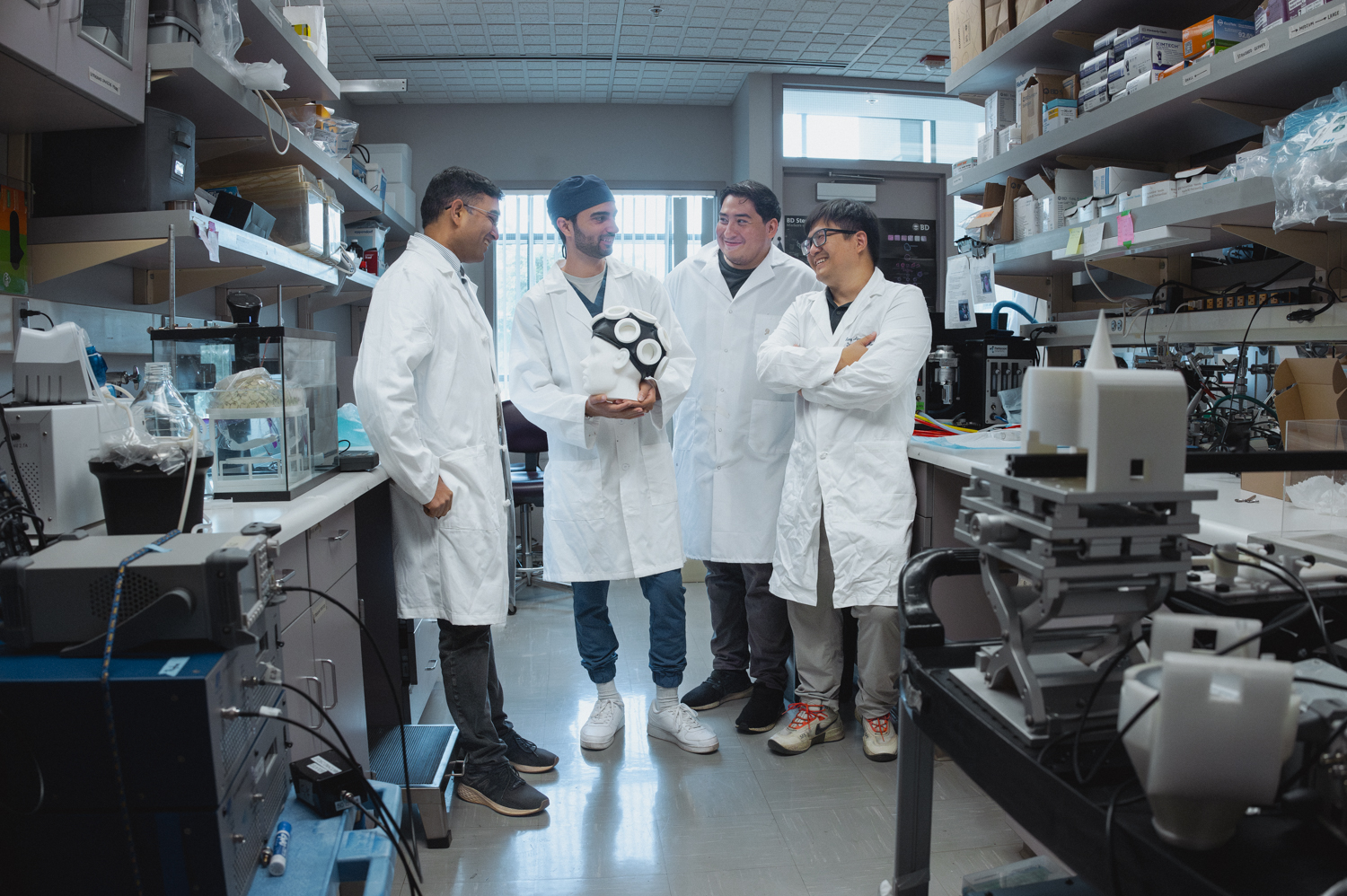 Raag Airan, Matine Azadian, Payton Martinez and Yun Xiang in the lab. Azadian is holding a version of their ultrasound apparatus.