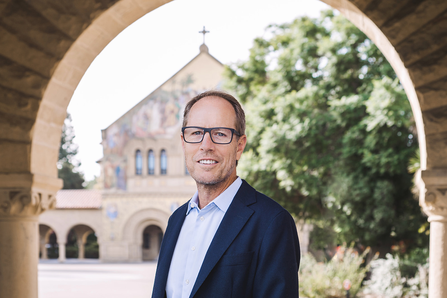Image of Tony Wyss-Coray posing for a photo under an archway in front of Memorial Church.