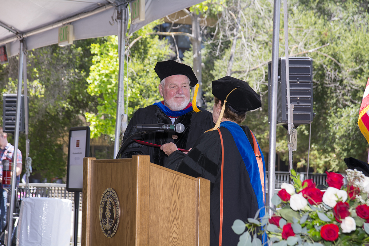 Gordon Brown in academic regalia receives an award at an outdoor ceremony beneath a tent.