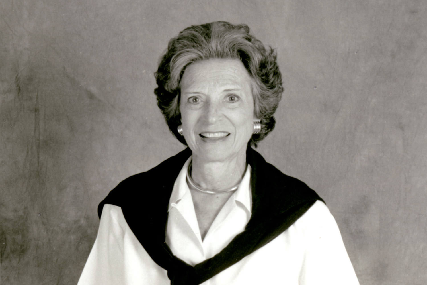 Doris Fisher white blouse and black sweater, posed against a gray background.