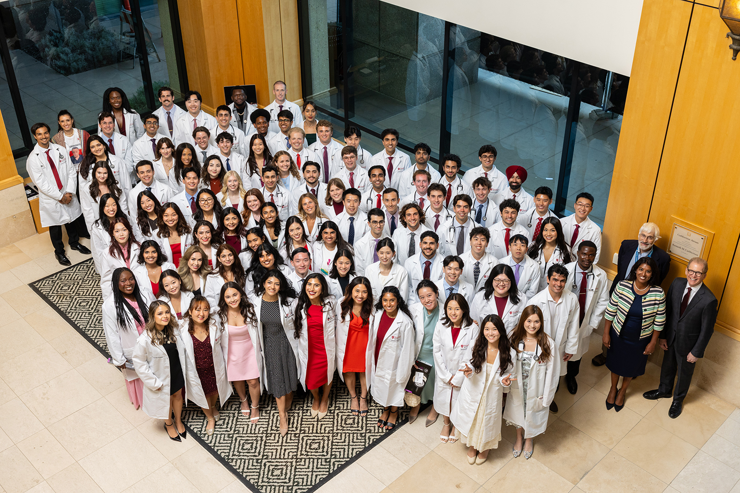 A large group of medical students in white coats poses together for a group photo.