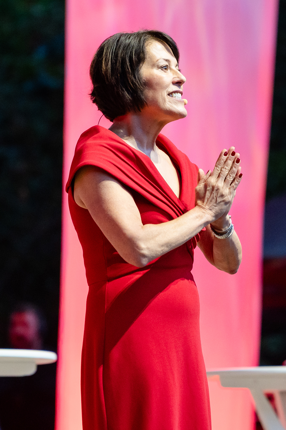 Dean Sarah Soule in red dress speaks from the stage at Frost Amphitheater.
