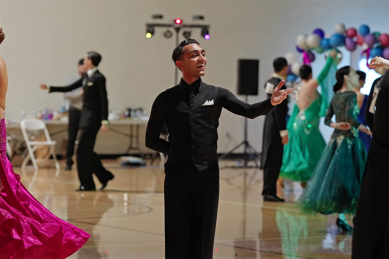 Open video Dancers in formal attire perform in a ballroom, with colorful dresses and a festive atmosphere featuring decorations in the background. in a modal