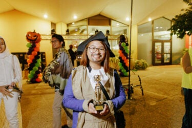 Student in costume holding a trophy