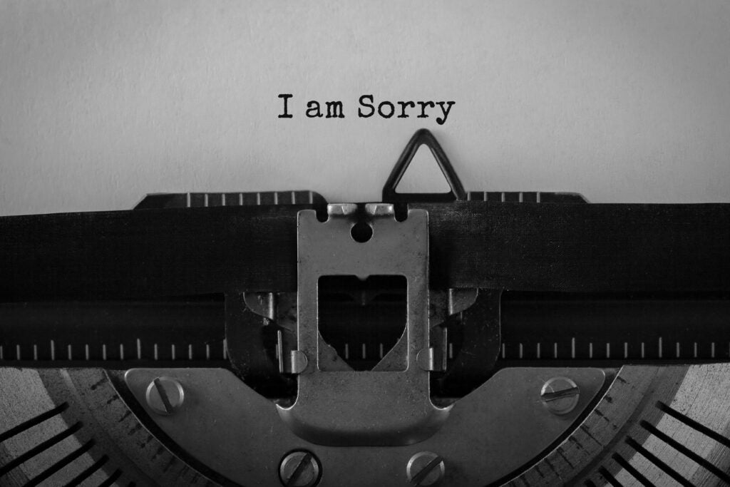A photo of a retro typewriter with a piece of paper in it. On the paper are the words "I am sorry."