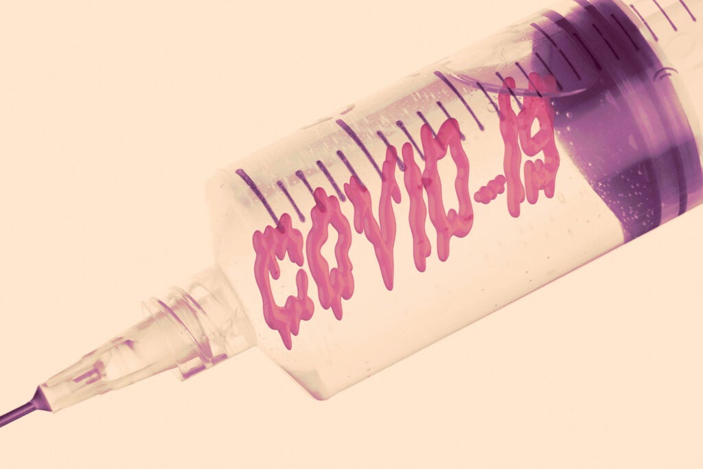 A photo-illustration of a syringe with "Covid-19" drawn on to look like liquid in the syringe.