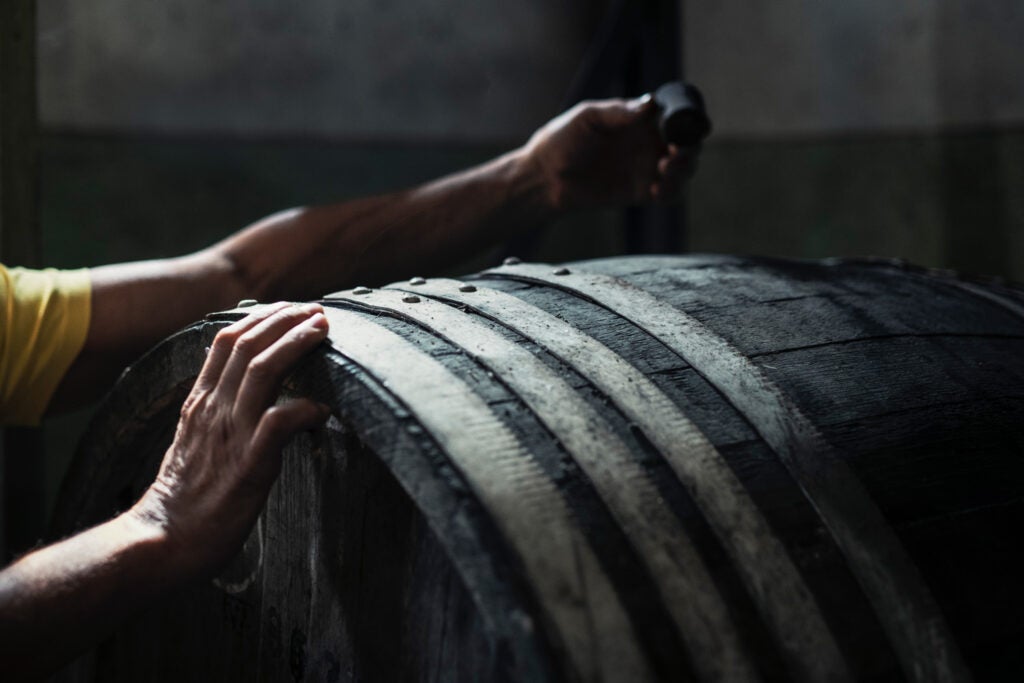 a close up photo of a man's hands doing quality control on an aging barrel.