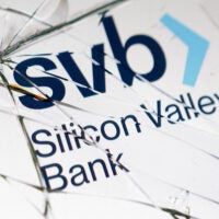 Silicon Valley Bank (SVB) logo is seen through the broken glass of an ATM machine.