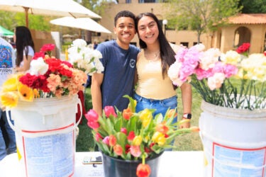 Two students at table with flowers.