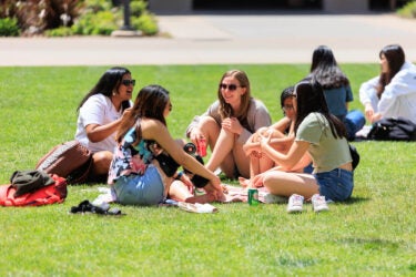 Students seated in a circle on the lawn.