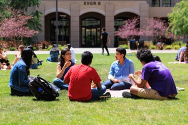 Students seated in a circle on the lawn.