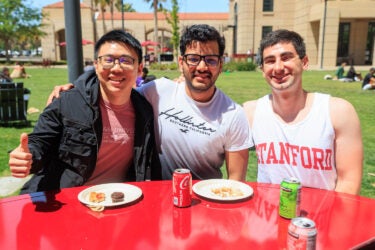 Three students seated at an outdoor table.