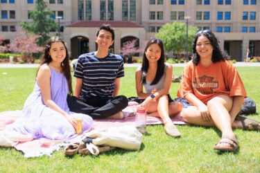 Four students seated on the lawn.