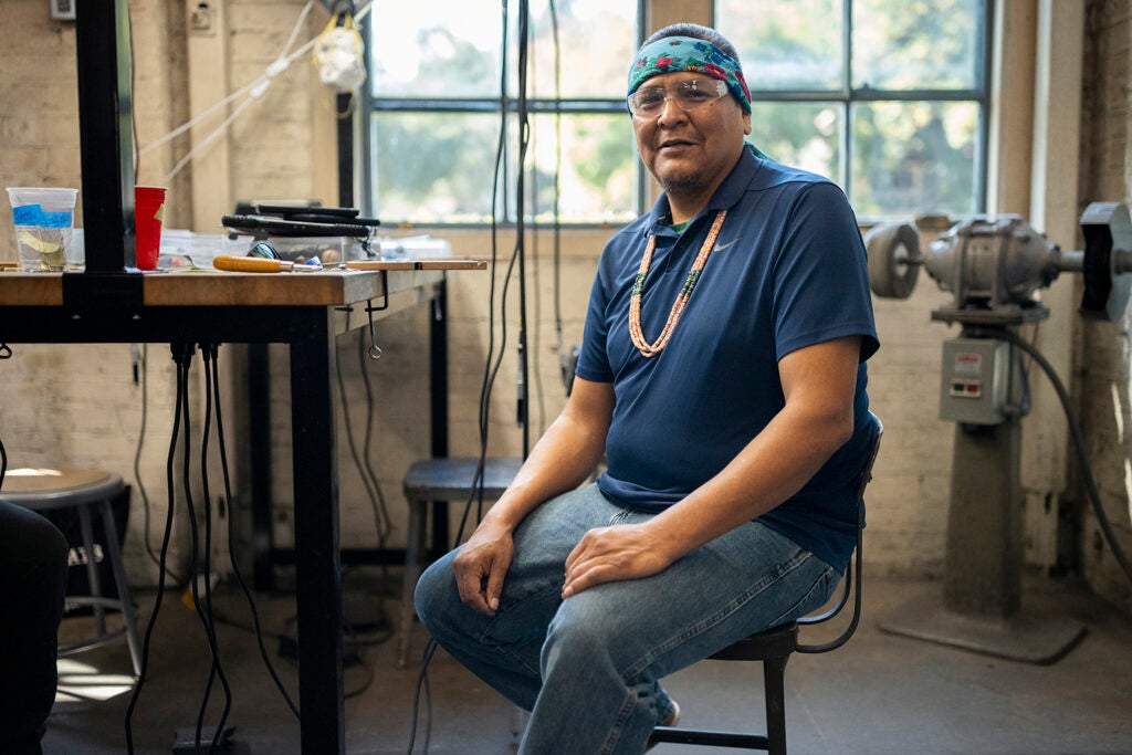 Robert Blackhat Jr. poses for a photo at the workbench during the Arts Intensive in September 2023.