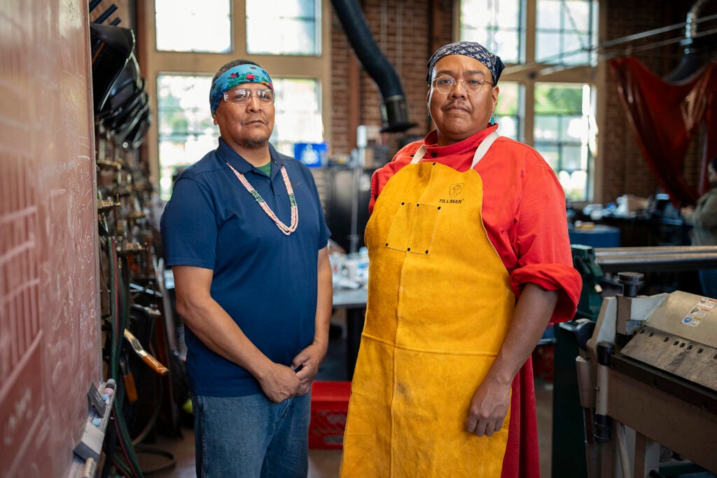 Navajo artists Robert Blackhat Jr. and Zefren Anderson pose for a portrait in the workshop.