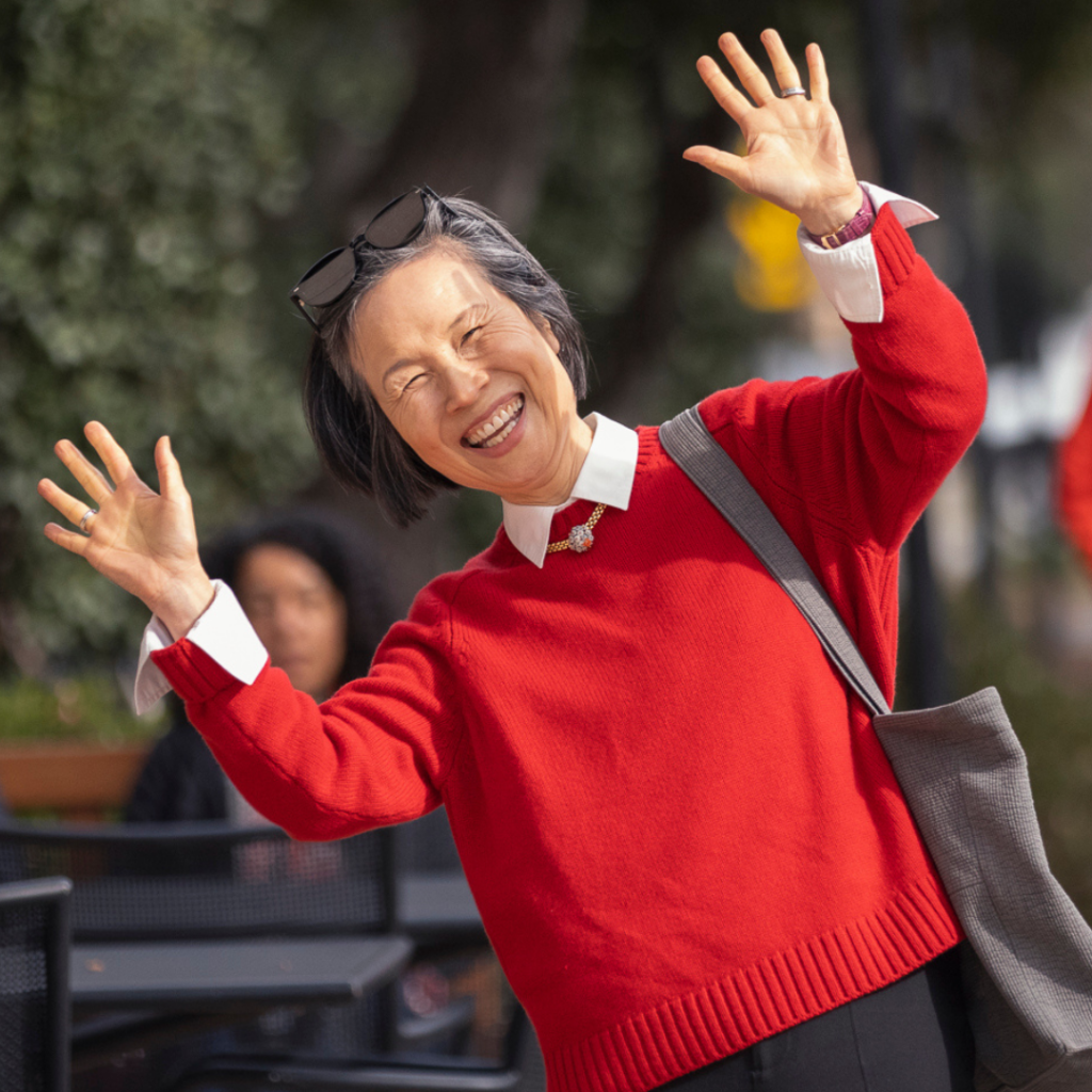 A visitor in a bright red sweater smiles for the camera after leaving a campus event during Family Weekend 2024