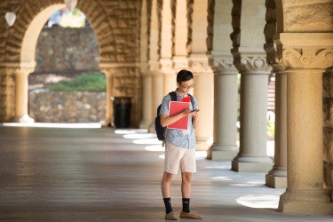 a student stands alone in the arcade of the main quad