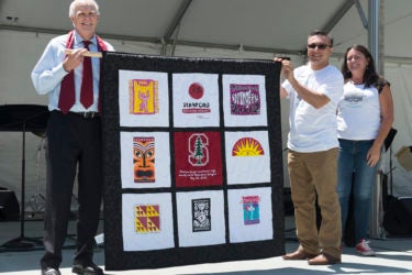 John Hennessy and Victor Madrigal holding a T-shirt quilt gift while Sheila Sanchez looks on