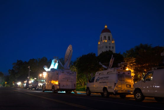 Media vans parked on street with Hoover Tower in background