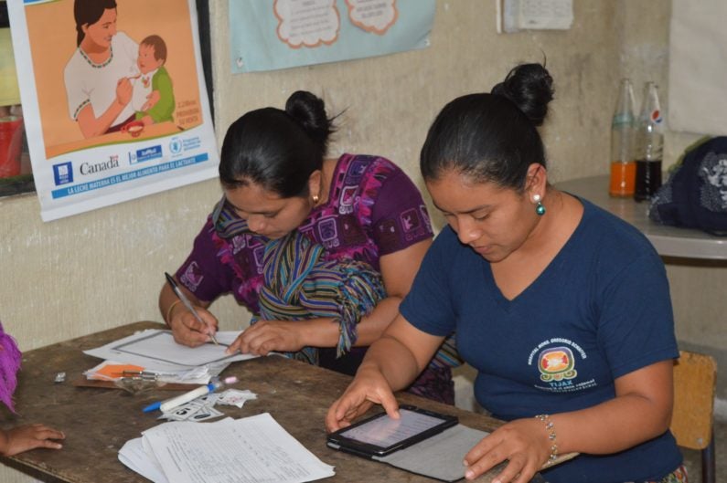 Health promoters with a tablet computer using app to track children's nutrtion
