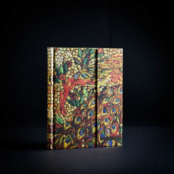 An ornate journal with a shimmery peacock pattern of golds, reds, blues and greens on the cover