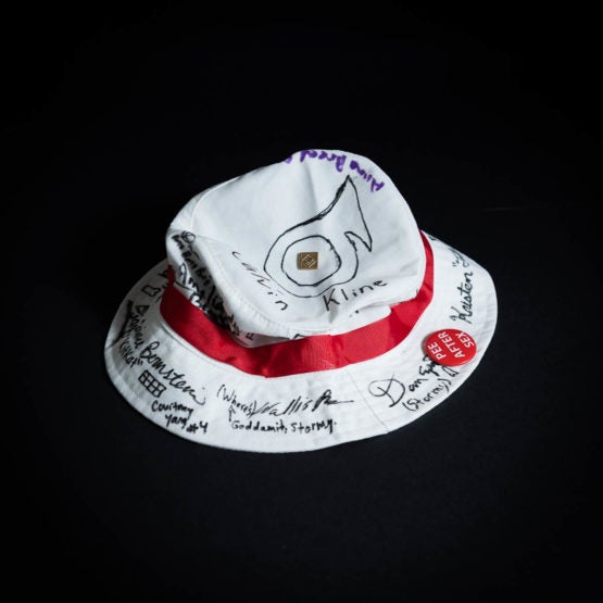 Band hat with signatures, a pin, and a button attached to it.