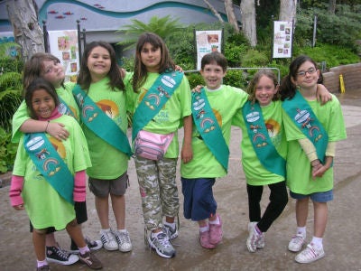 A row of Girl Scouts in green T-shirts and Scout sashes