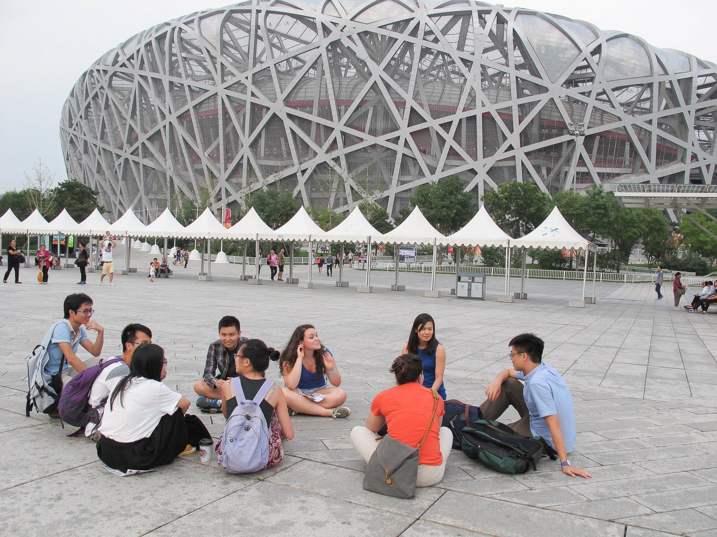 class sitting in discussion outside the Bird's Nest stadium at Olympic Village in Beijing