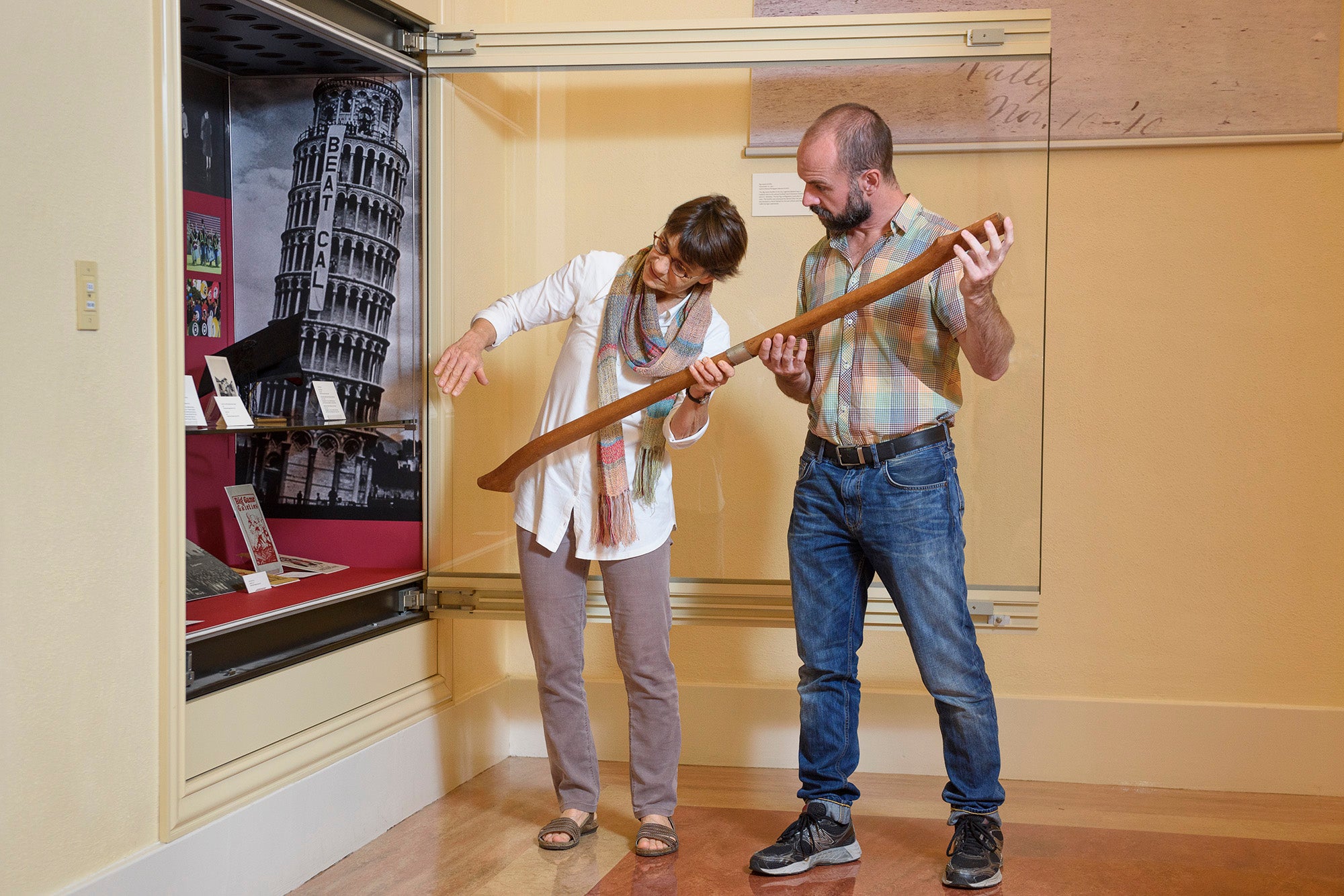 Exhibition designer Becky Fischbach and archivist Daniel Hartwig placing handle of Stanford Axe in display case at Green Library