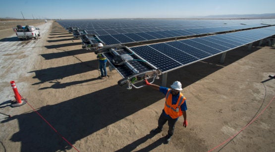 Workers starting a robot on a solar panel.