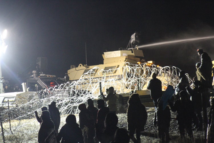 Law enforcement personnel fire a water cannon at Standing Rock protestors in sub-zero temperature.