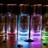 bottles glow in rainbow colors as laser causes nanoparticles suspended in cyclohexane to emit light