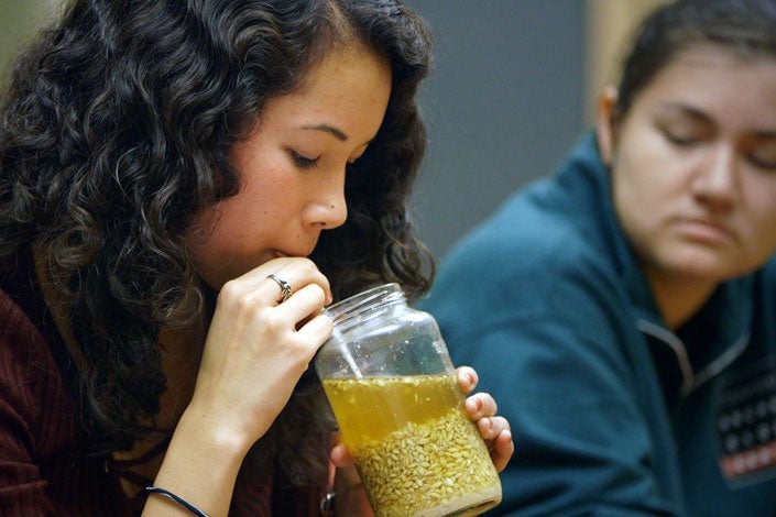 Student sipping through a straw a self-brewed beer from an ancient recipe