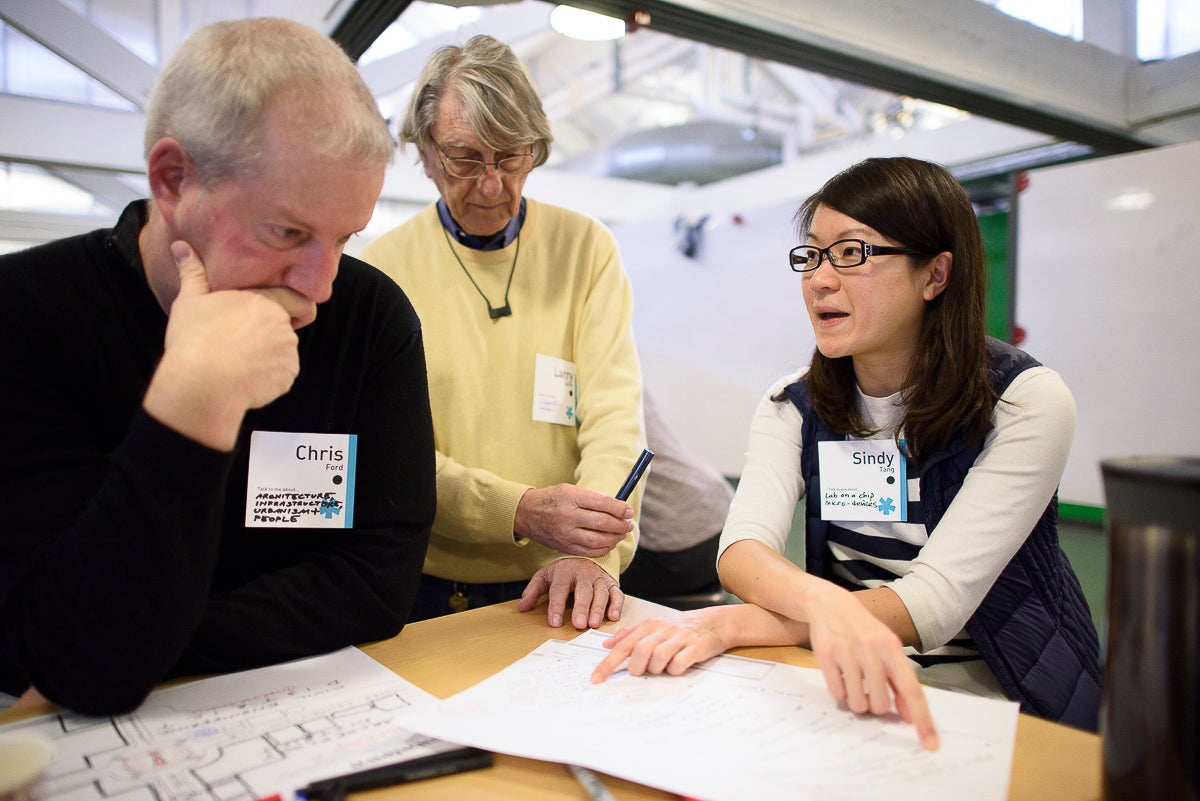 Chris Ford, Larry Leifer and Sindy Tang around a desk working on an exercises in the Catalyst workshop.