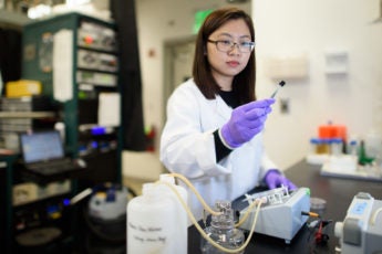Chong Liu examines a carbon-amidoxime electrode before assembling it into the flow device.