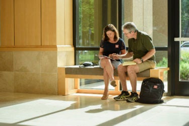 Parents Ginger and John O’Neil of Midlothian, Virginia, consult registration info to plan their weekend after dropping off their daughter at Arrillaga Alumni Center