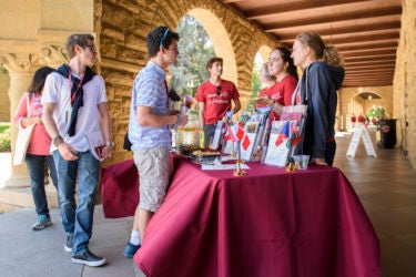 Students talk at an information table in the Main Quad