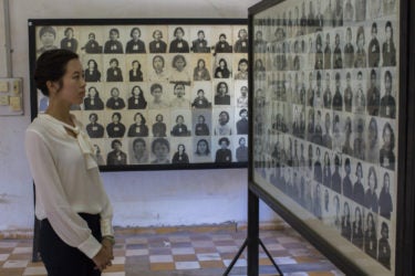 a young woman viewing walls of photos of victims of the genocide