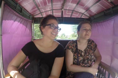 two woman seated in a narrow carriage covered with fabric